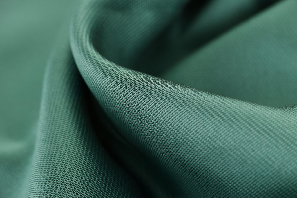 Close-up texture shot of elegant green satin fabric highlighting its smooth and soft surface.