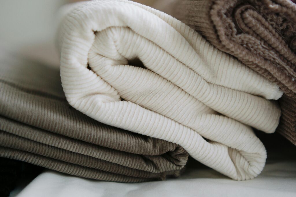 Stack of folded corduroy fabrics in beige and brown, perfect for textile projects.